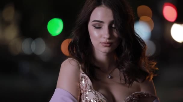Beautiful attractive woman looking at camera in night city, slow motion — Stock Video