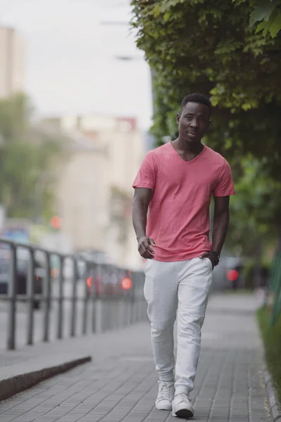 African american man in living coral t-shirt walking at city — Stock Photo, Image