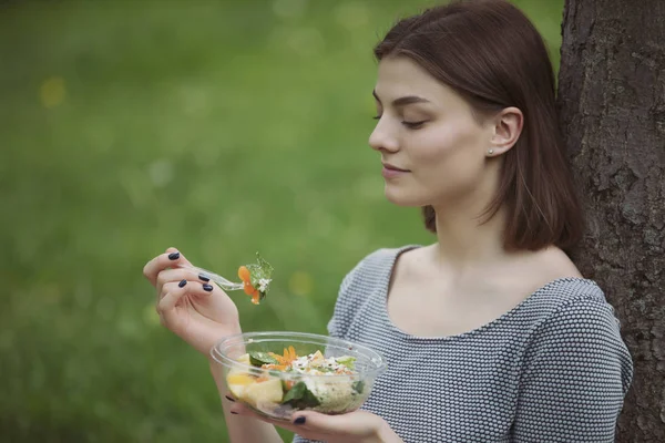 Kvinna äter fräsch sallad sitter på Summer Park — Stockfoto