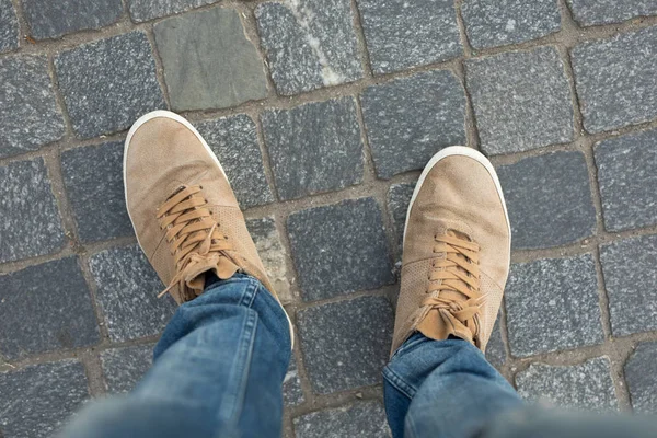 POV of male gumshoes on paving slabs Stock Photo