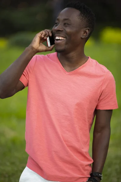 African american man in living coral t-shirt talking by smartphone