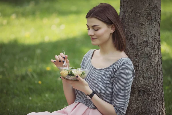 Kvinna äter fräsch sallad sitter på Summer Park — Stockfoto