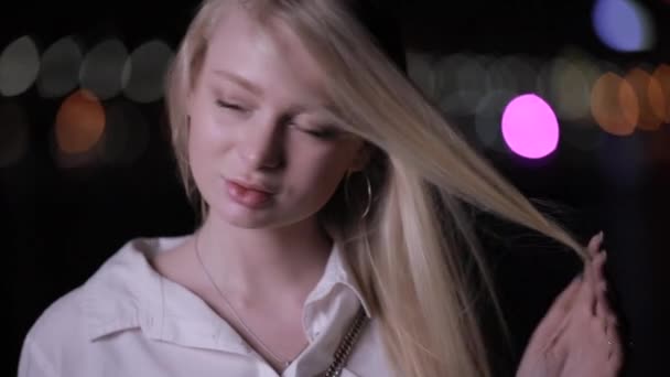 Seksowna blondynka stwarzająca Dotykanie długich włosów w nocnym mieście — Wideo stockowe