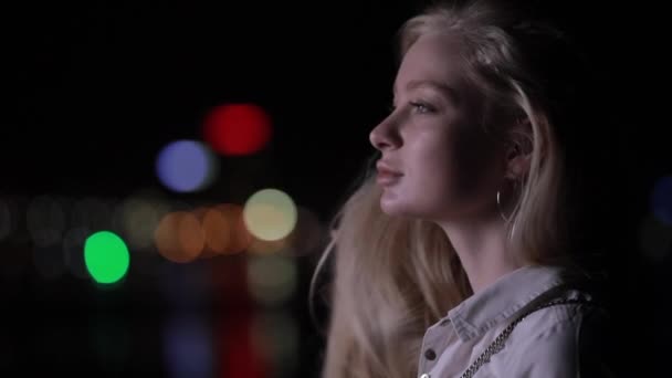 Smuk blondine kvinde røre ved hendes lange hår i nat by – Stock-video