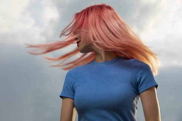 Woman toss her pink hair over sky background