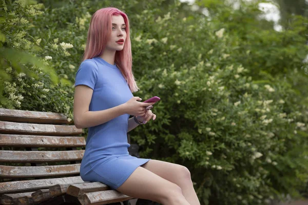 Unconventional woman with pink hair using smartphone on bench — Stock Photo, Image