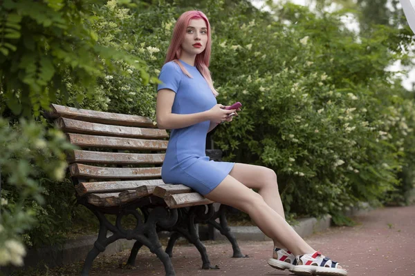 Mulher não convencional com cabelo rosa usando smartphone no banco — Fotografia de Stock