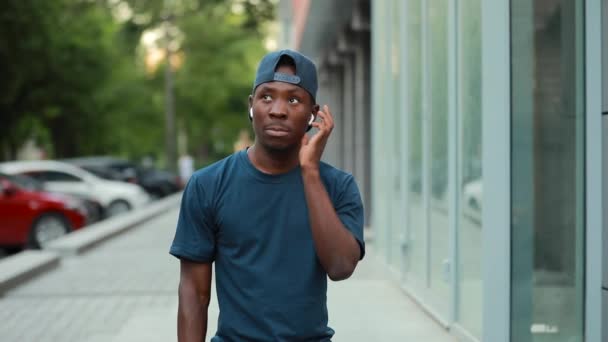 アフリカの男性は、選択の音楽のためのワイヤレスイヤホンをクリック — ストック動画