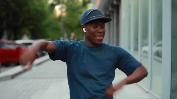 Hombre africano feliz bailando en la ciudad escuchando música en auriculares — Vídeos de Stock