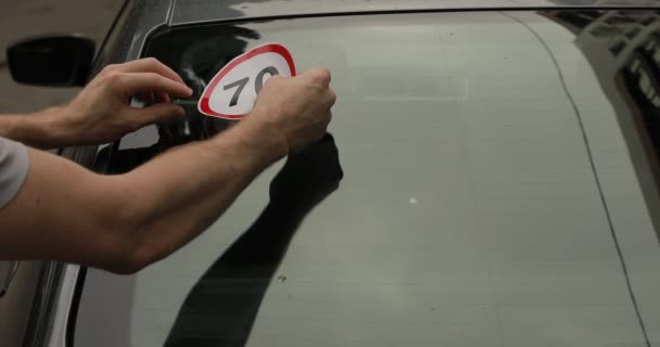 Водитель прикрепляет табличку 70 км / ч к окну своей машины — стоковое видео