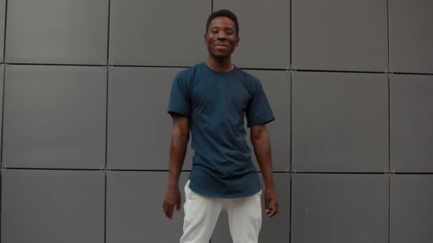 Африканский мужчина танцует у стены здания — стоковое видео