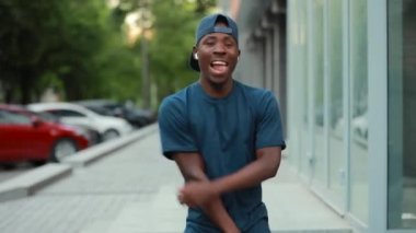 Mutlu Afrikalı adam şehirde müzik kulaklık la dinleyerek dans