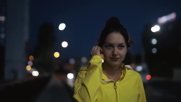 Femme sportive met des écouteurs sans fil et court sur un pont — Video