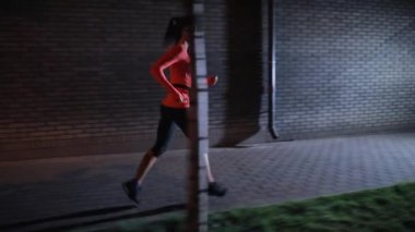 Spor kadın kulaklıklar ile gece şehir sokak boyunca çalışan