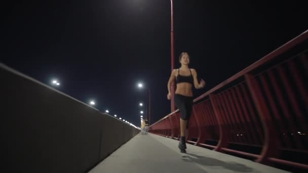 Femme sportive courant le long du pont de nuit — Video