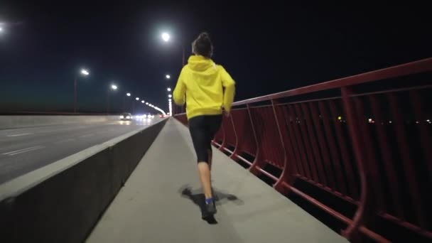 Esporte mulher correndo ao longo da ponte noturna, visão traseira — Vídeo de Stock