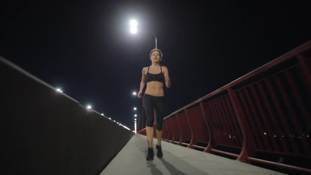Спортивная женщина бегает по ночному мосту — стоковое видео