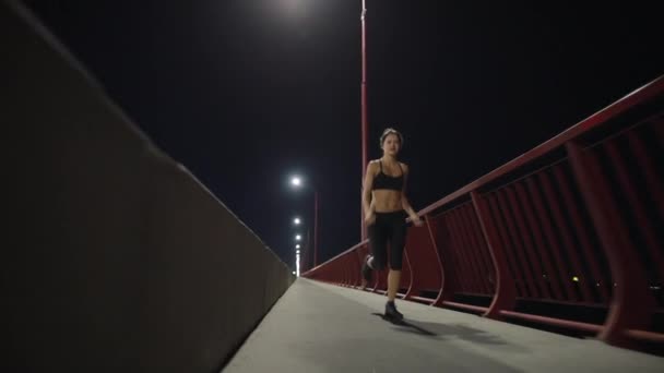 Sport vrouw loopt langs Night Bridge — Stockvideo