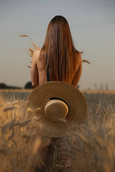 Rücken einer nackten Frau auf einem Feld mit Hut — Stockfoto