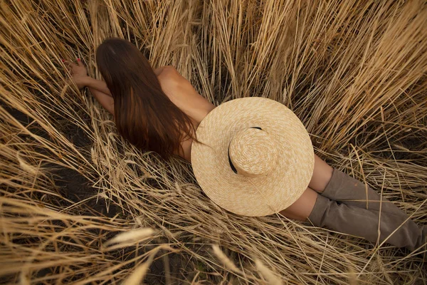 Meztelen nő feküdt egy mezőn kalappal — Stock Fotó