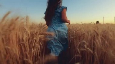 Bir buğday tarlası üzerinde ileri koşan kadın, yavaş hareket