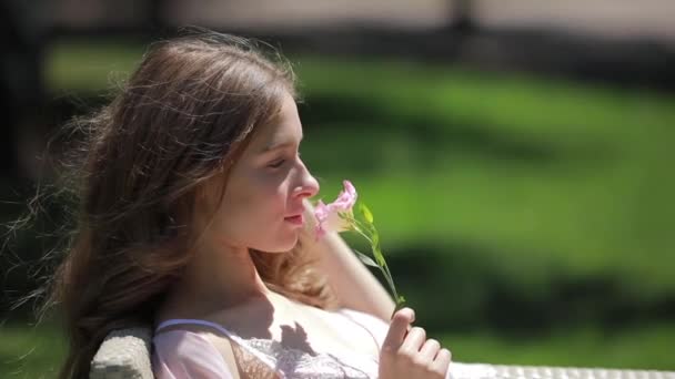 Modelo mirando hermosa flor sentada en el jardín — Vídeo de stock