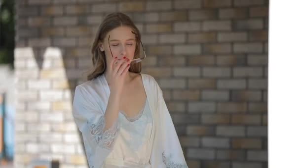 Schönes Model in Peignoir mit Brille, das auf dem luxuriösen Hausgarten spaziert — Stockvideo