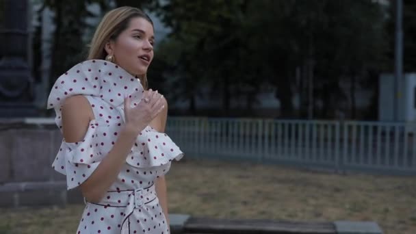 Belle femme heureuse en robe marchant dans l'allée de la ville d'été, au ralenti — Video