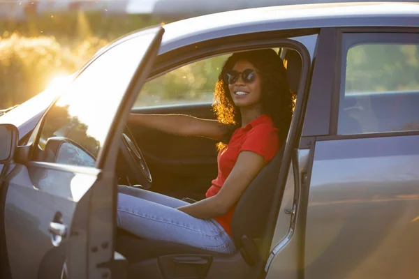 Glückliche Autofahrerin sitzt bei Sonnenuntergang im Autosalon — Stockfoto