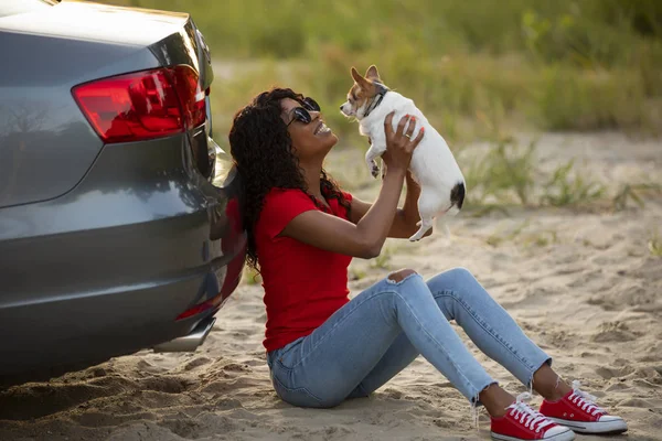 Mujer jugar con su perro sentado cerca de coche — Foto de Stock