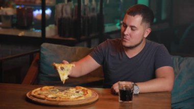 Bir barda pizza yiyen adam