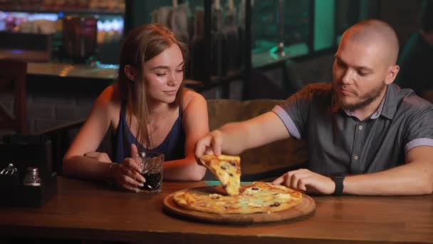 Pareja comiendo pizza malsana en un bar — Vídeos de Stock