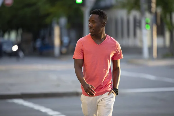 Şehirde yürüyüş yaşayan mercan t-shirt Afrikalı Amerikalı adam — Stok fotoğraf