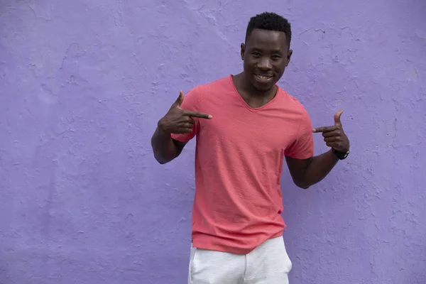 Modelo de hombre afroamericano posando en una camiseta de coral viva vacía en la pared violeta — Foto de Stock