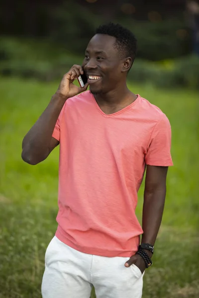 African american man in living coral t-shirt talking by smartphone