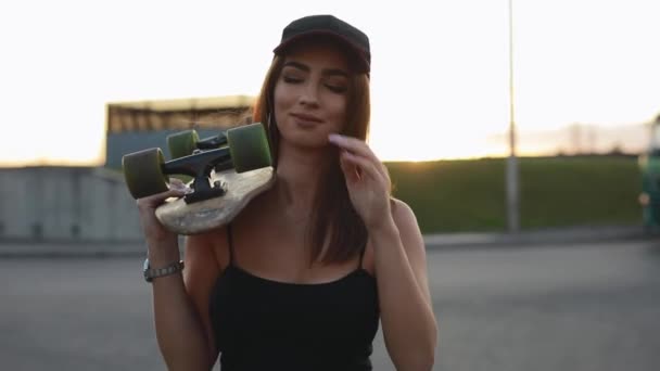 Woman skateboarder carries her skateboard on a shoulder — Stock Video