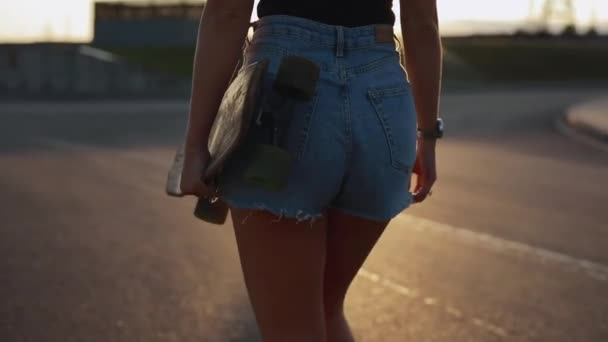 Skateboarder donna porta skateboard al tramonto — Video Stock