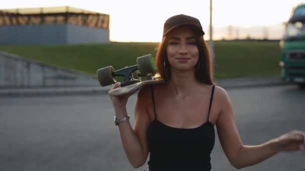 Woman skateboarder carries her skateboard on a shoulder — Stock Video