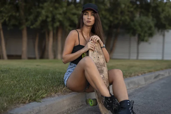 Jeune femme skateboarder assis avec son skateboard — Photo