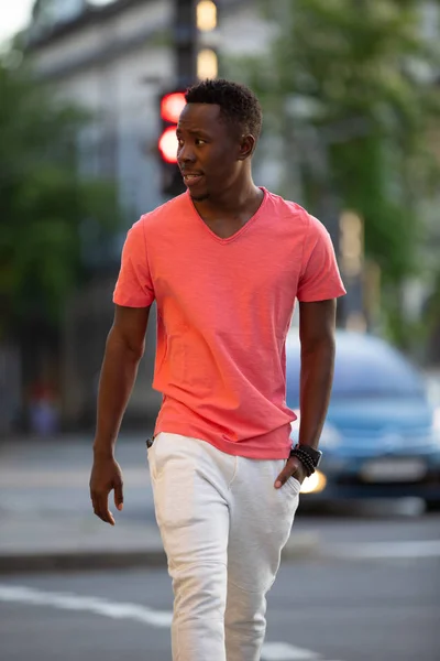 Афроамериканець людина в живих коралових футболку ходити в місто — стокове фото