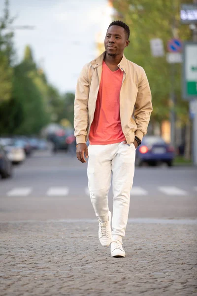 African american man in living coral t-shirt walking at city — Stock Photo, Image