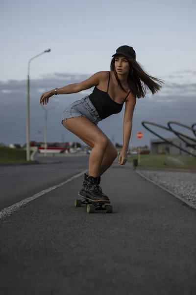 Mulher skatista montando seu skate em uma estrada — Fotografia de Stock