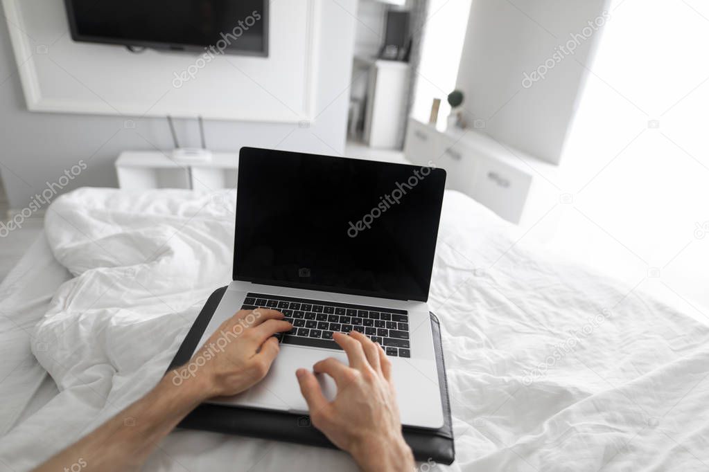 1st person view man using laptop in a bed