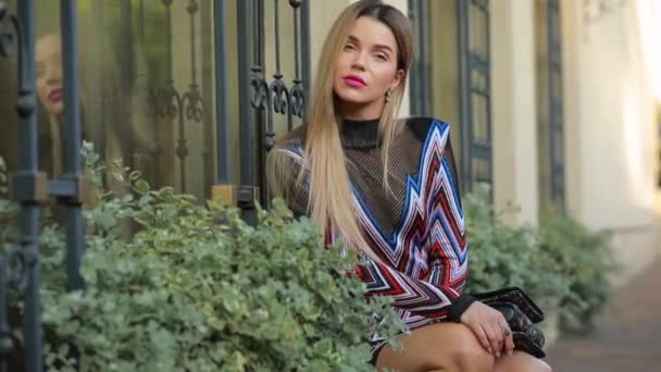 Gyönyörű divatos luxus női modell pózol ülés közelében épület külső — Stock videók
