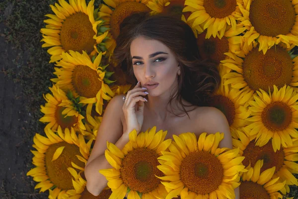 Beauty portrait of woman lying in sunflowers — Stock Photo, Image