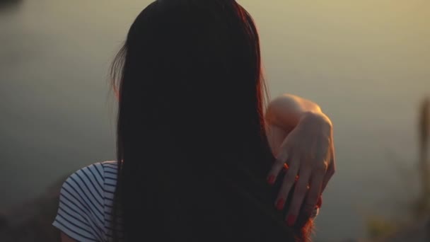 Γυναίκα κάθεται και αγγίζει τα μαλλιά και τον ώμο χαλάρωση στη φύση — Αρχείο Βίντεο