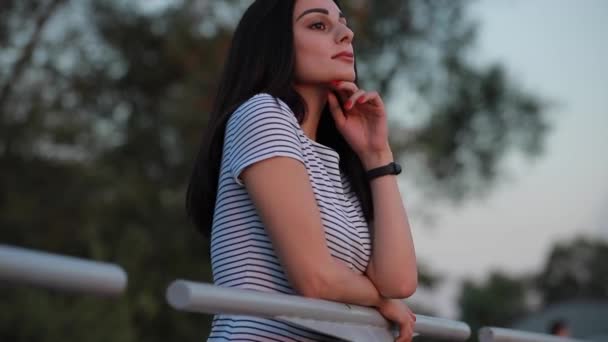 Mujer bonita de pie mirando hacia el atardecer y pensando — Vídeos de Stock