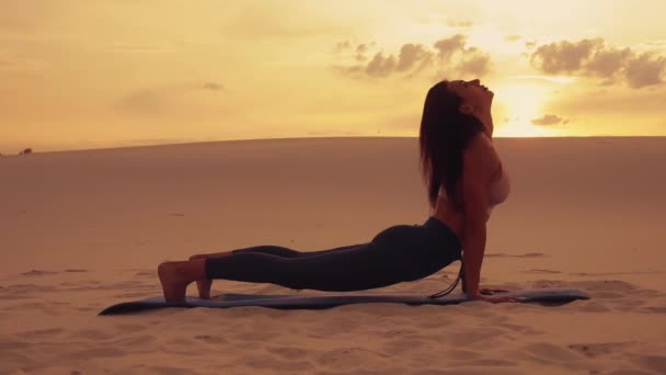 Kvinna gör yoga övning i öknen vid solnedgången — Stockvideo