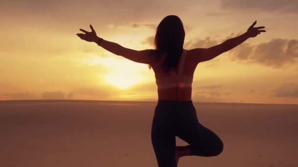 Silhueta de mulher meditando ioga balanceamento de pé sobre a perna no deserto — Vídeo de Stock