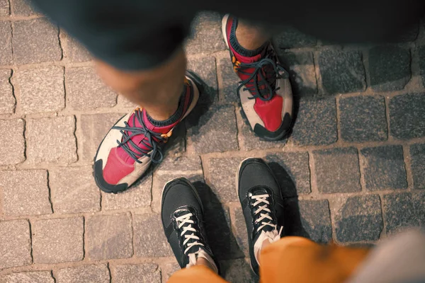 Couple legs in footwear on pavement, pov view from above — Stock Photo, Image